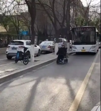  银川老人乘轮椅前行,身后跟着公交车队